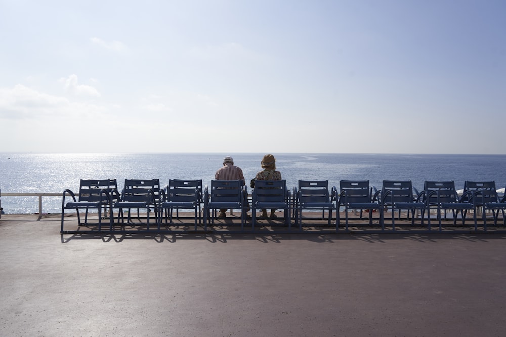 two people sitting on a bench looking out at the ocean