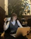 A friendly professional woman at a desk with a laptop and a cup of coffee, ready to assist clients.