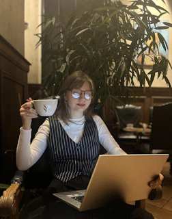 A confident woman entrepreneur working on her laptop with a cup of coffee nearby in a cozy home office.