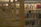 A library aisle with neatly aligned books on wooden shelves. The shelves are filled with a variety of books, with a focus on fiction and non-fiction genres. The environment is well-lit, providing a quiet and organized atmosphere typical of a library setting.