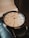 A luxury wristwatch with a sleek, polished metal case and a detailed, textured dial. The watch has gold hour markers, including Roman numerals and diamond accents at select positions. The hands are finely crafted and the brand name is visible on the dial.