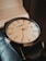 A luxury wristwatch with a sleek, polished metal case and a detailed, textured dial. The watch has gold hour markers, including Roman numerals and diamond accents at select positions. The hands are finely crafted and the brand name is visible on the dial.