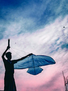 Close-up of hands holding kite strings with vibrant kites flying in background