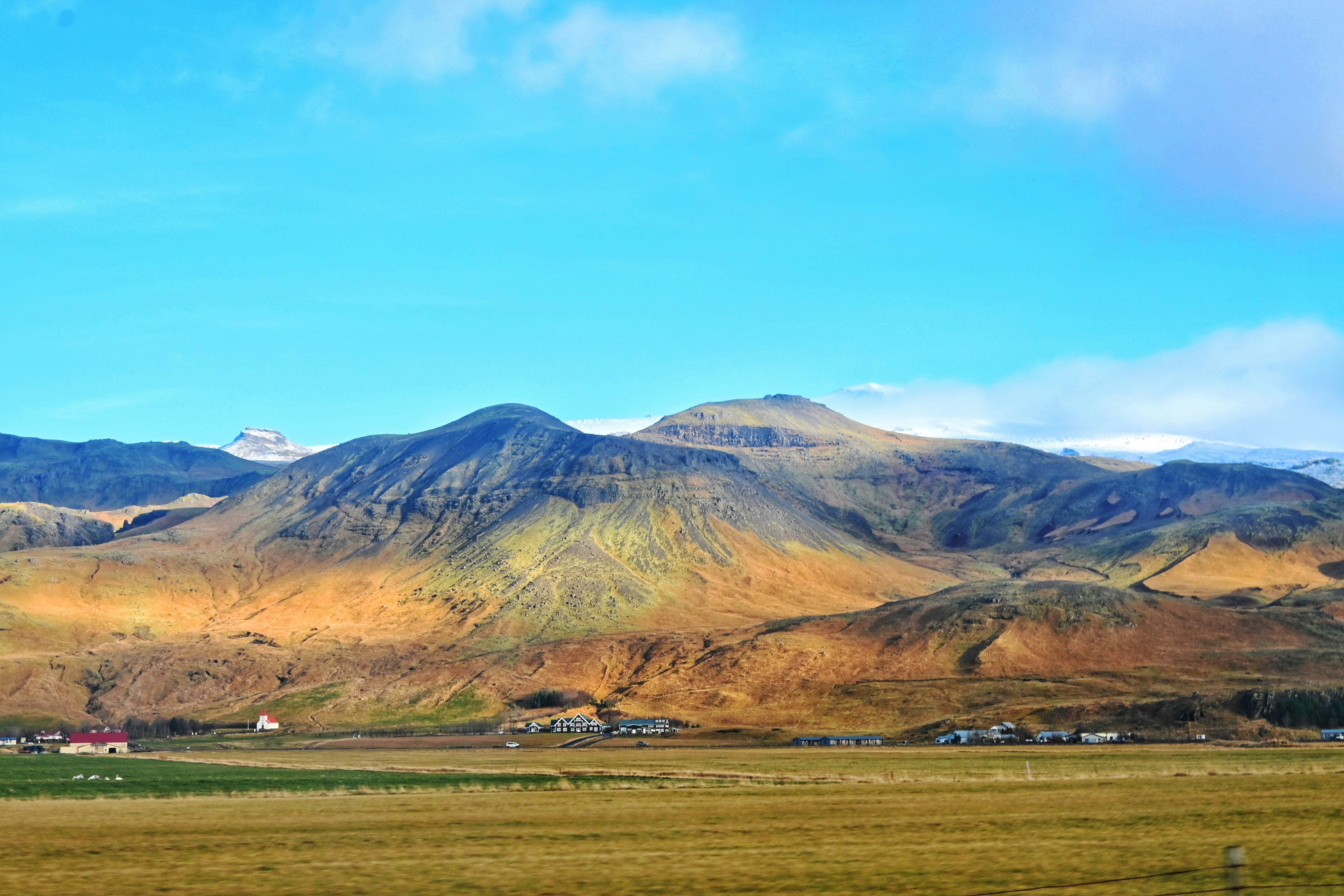 a view of a mountain range with houses in the foreground, Iceland Landscapes