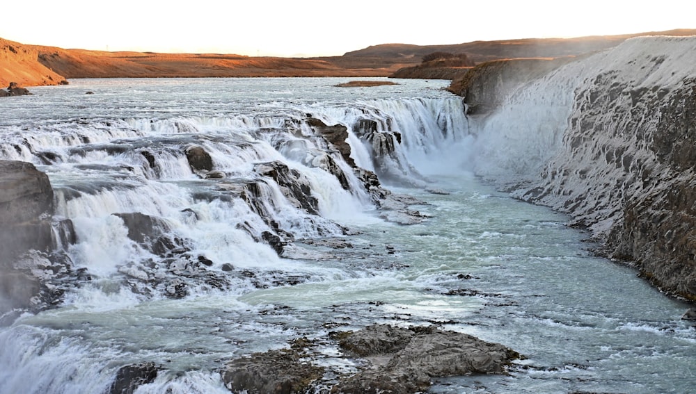 a large waterfall that is next to a body of water