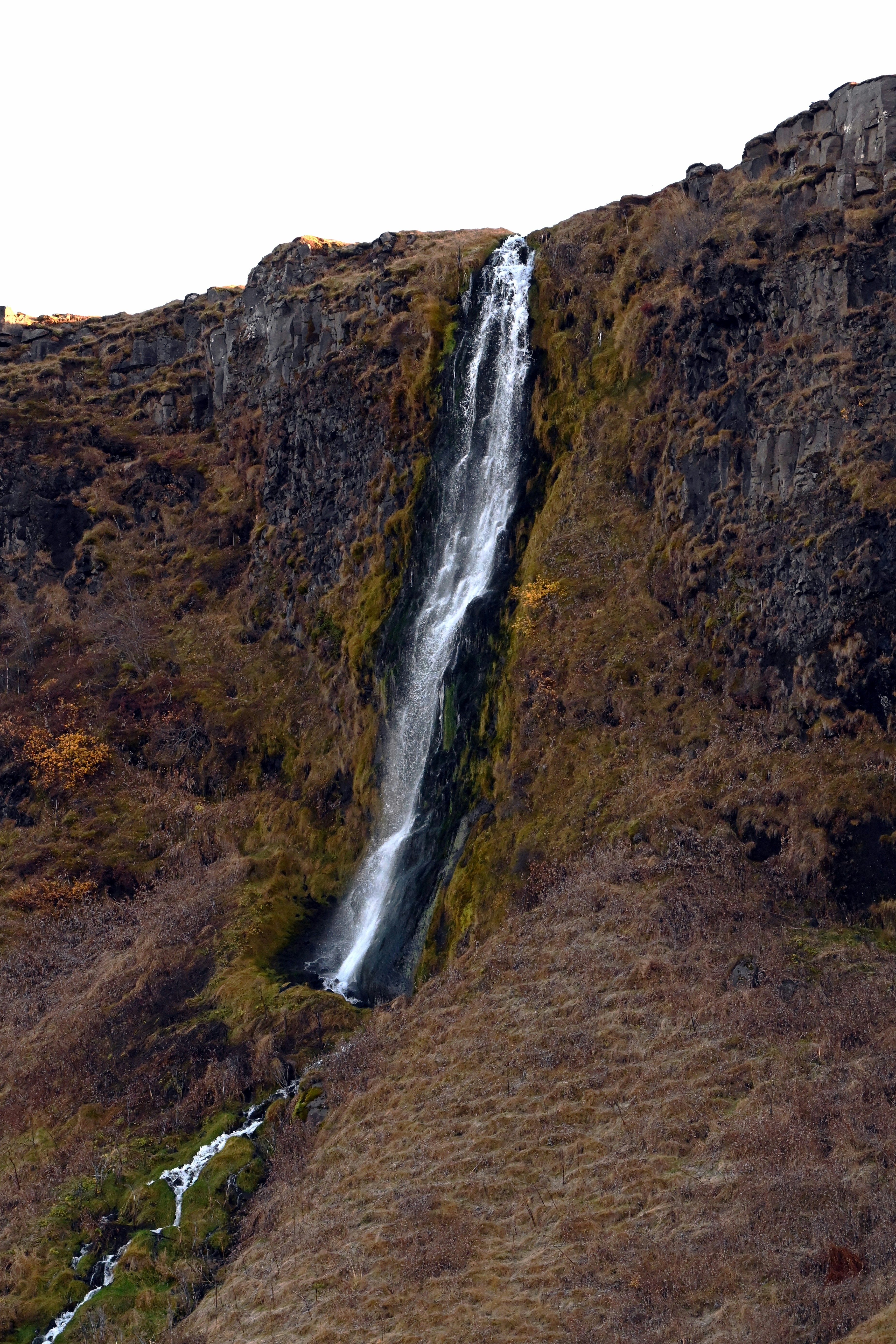 a very tall waterfall in the middle of a field