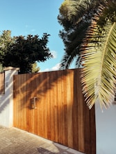 Aluminium gate at the entrance of a home surrounded by greenery on a sunny day.
