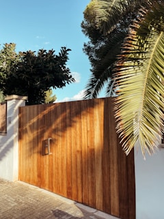 A close-up of a wooden gate with clean lines and a natural finish surrounded by trimmed shrubs