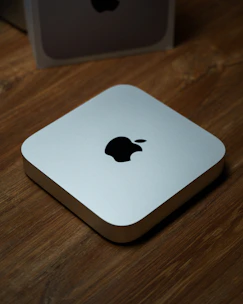 Close-up of a sleek 3D printed Mac Mini stand with a matte finish on a wooden desk.