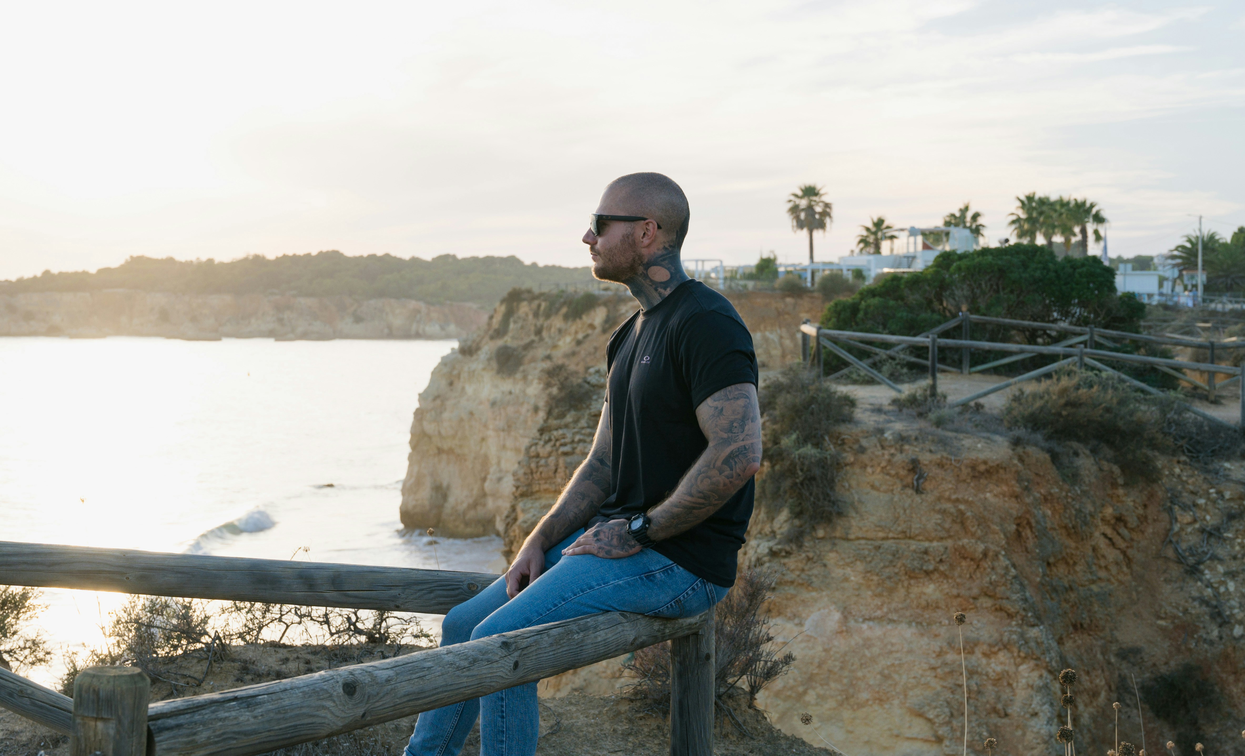 a man sitting on a rail overlooking a body of water