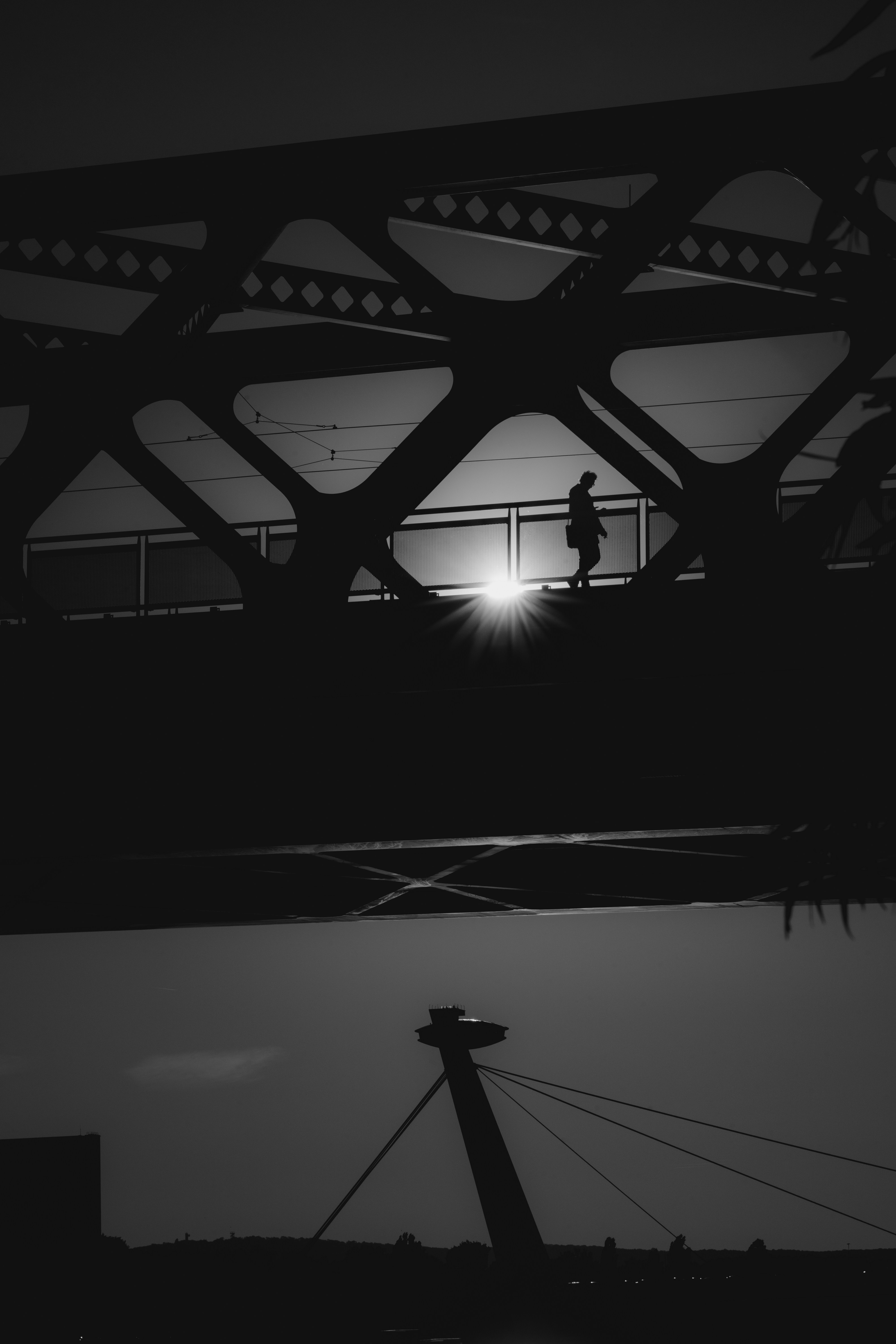 a black and white photo of a person running across a bridge