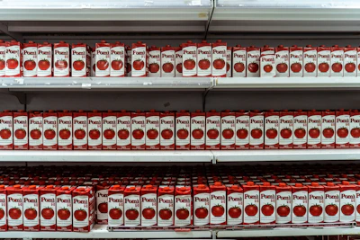 Stacked tins of tomato paste in different sizes with bright red labels, highlighting packaging variety.