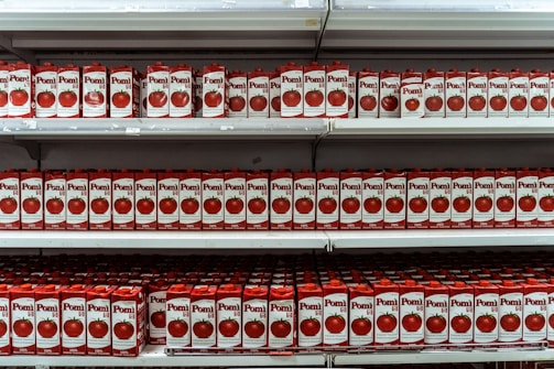 Assortment of canned tomato paste, vegetables, and condensed milk neatly arranged