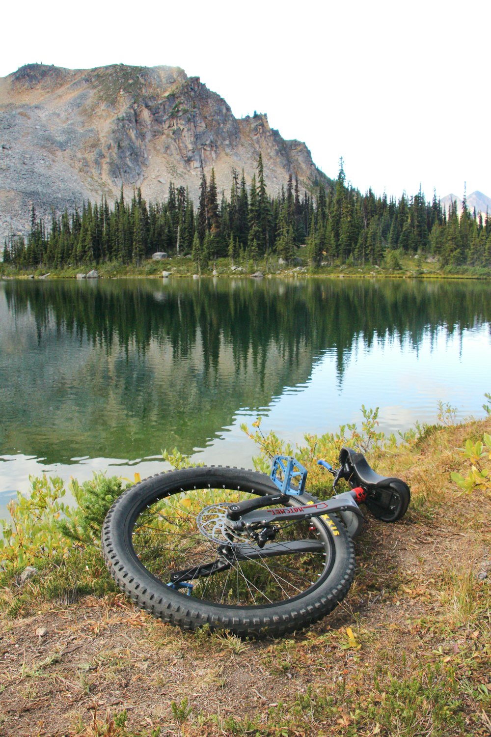 a bicycle is parked on the shore of a lake