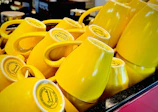 A set of pastel yellow coffee cups stacked neatly on a cozy kitchen shelf with soft natural lighting.