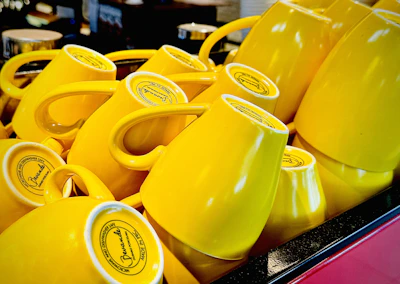 A set of pastel yellow coffee cups stacked neatly on a cozy kitchen shelf with soft natural lighting.