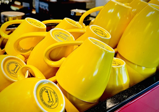 A colorful set of ceramic mugs stacked playfully against a bright, sunlit kitchen backdrop