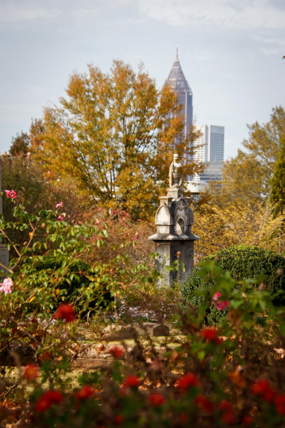 a statue in the middle of a garden with a city in the background
