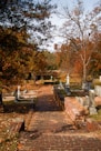 a brick path leading to a cemetery with a clock tower in the background