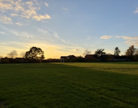 the sun is setting over a field of grass