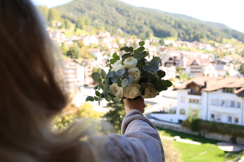 uma mulher segurando um buquê de flores na mão