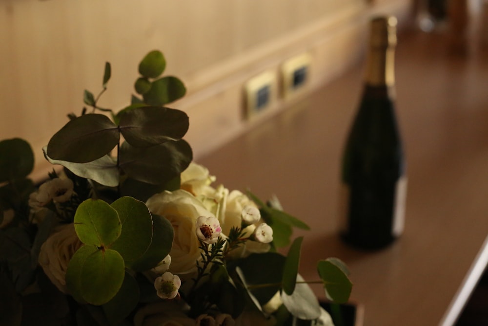 a bouquet of flowers sitting next to a bottle of wine