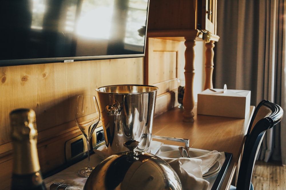 uma mesa coberta com uma taça de prata e uma garrafa de vinho