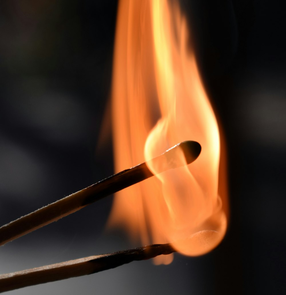 a close up of a matchstick with fire in the background