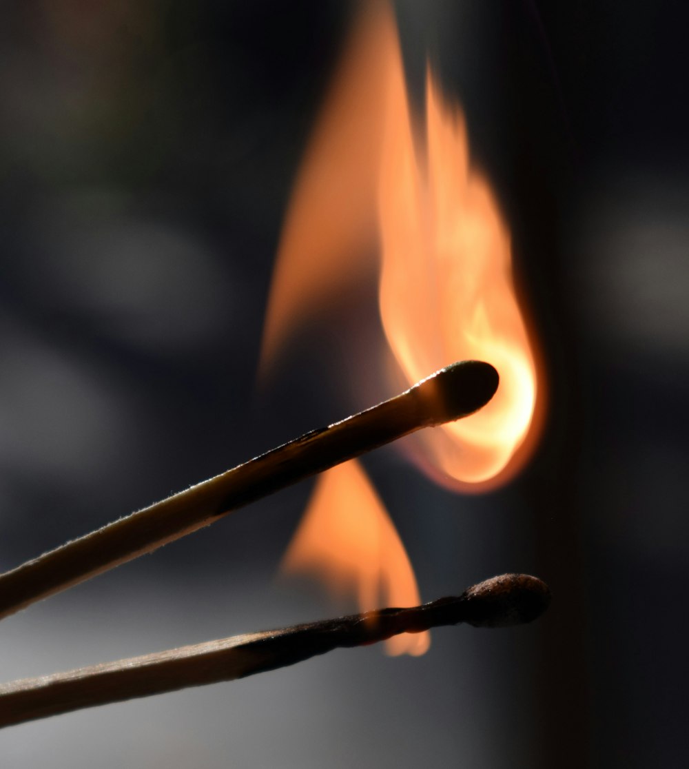 a close up of a matchstick with fire in the background