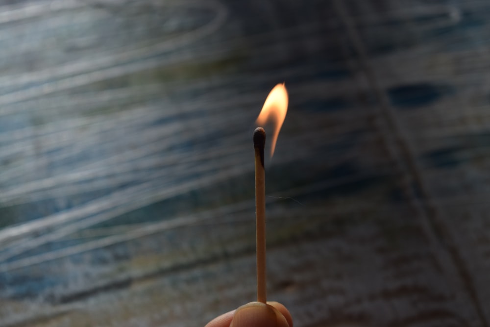 a hand holding a match stick with a lit match