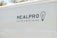 The side of a white vehicle displays the meal service logo 'MEALPRO' with the tagline 'For the Athlete in You'. Next to the text is a graphic combining a lightbulb and a fork.