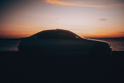 A vibrant sunset with a car parked on a beach.