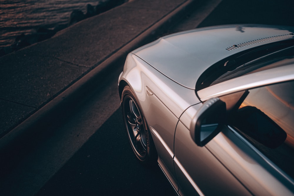 a silver car driving down a street next to a body of water