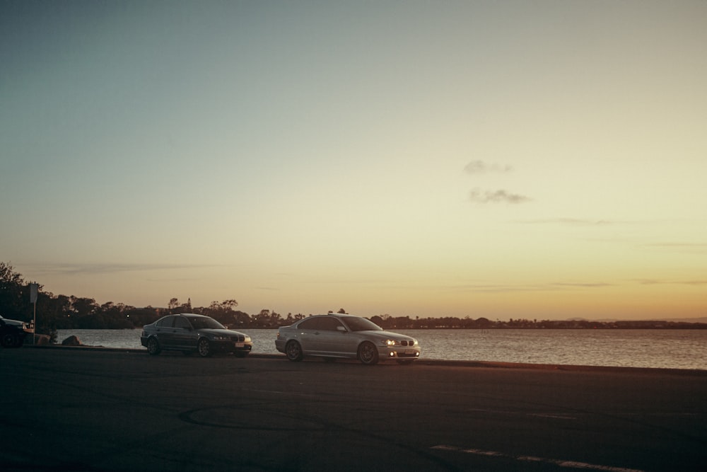 a couple of cars parked next to a body of water