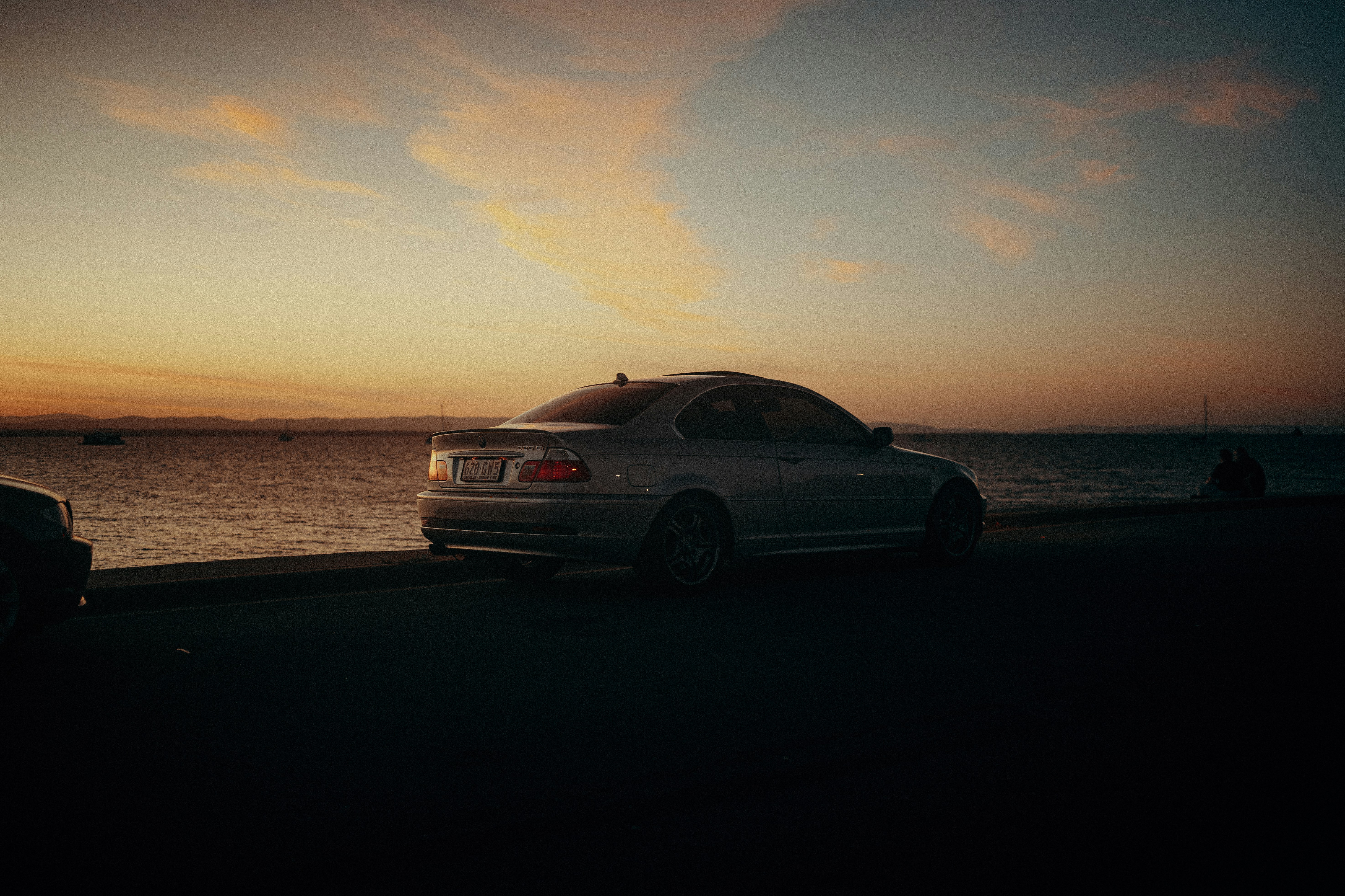 une voiture garée sur le bord d’une route au bord de l’océan
