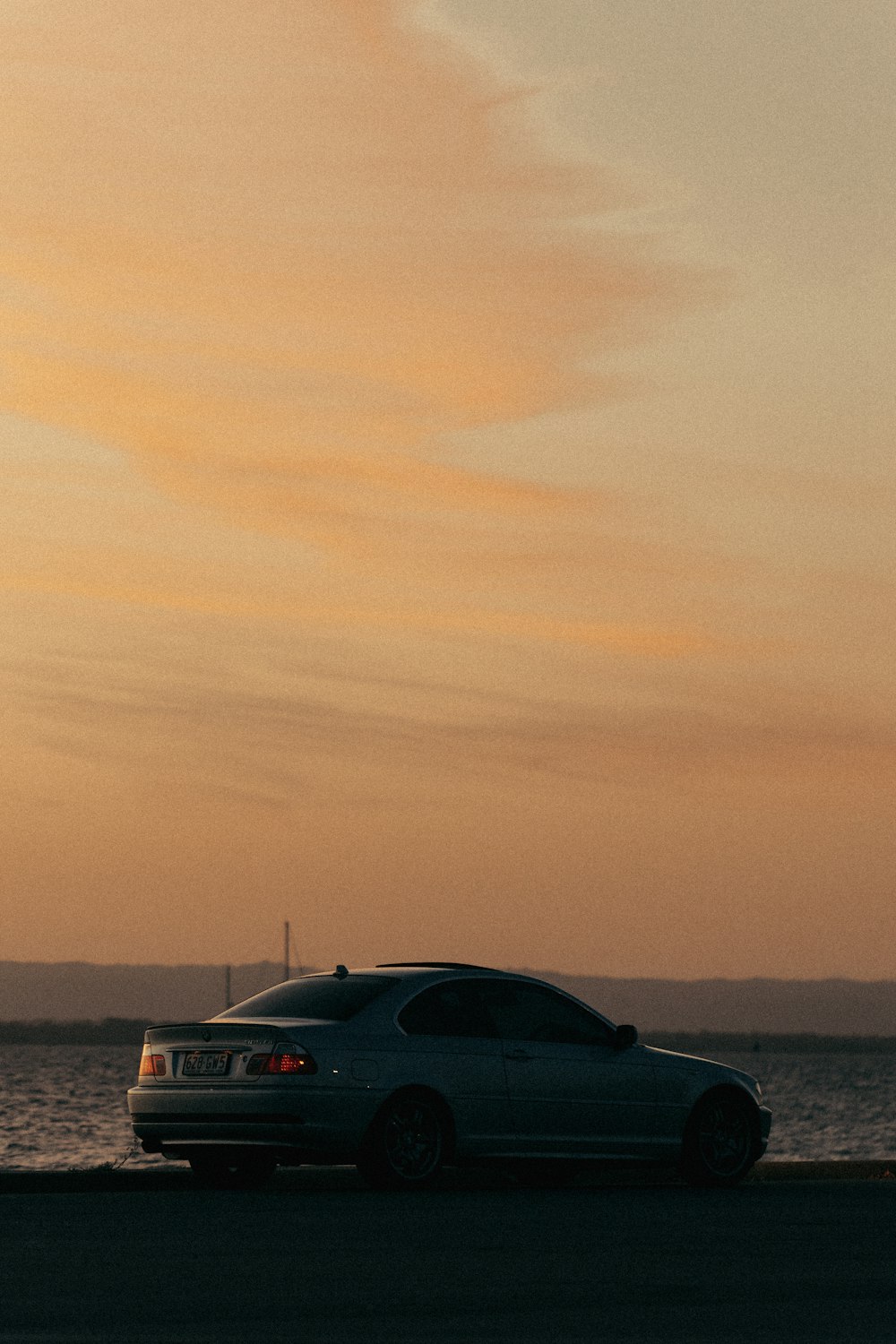 a car parked on the side of the road near the water