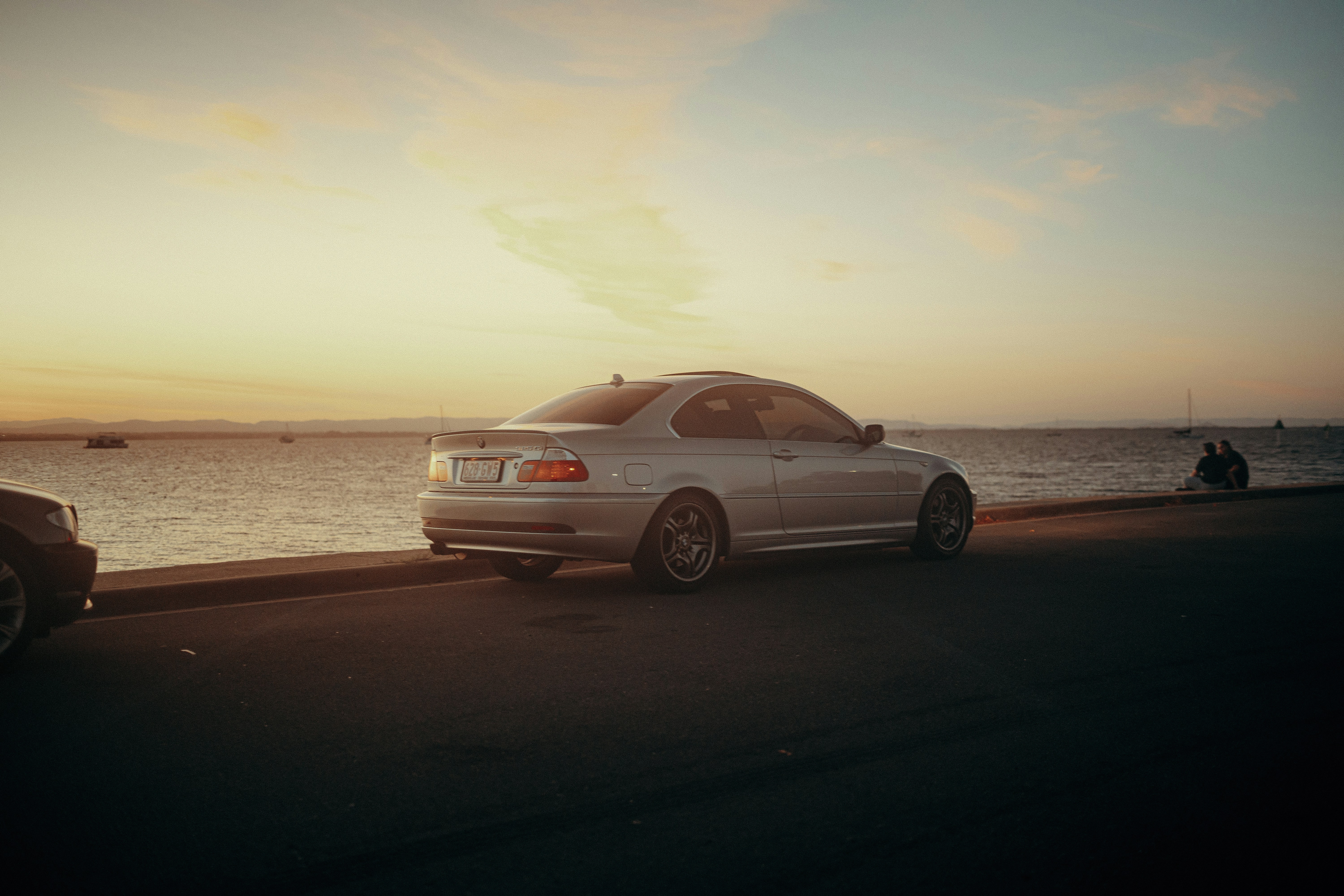 Une voiture blanche garée sur le bord d’une route au bord de l’océan