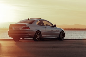 A luxury sedan parked beside a serene lake during golden hour