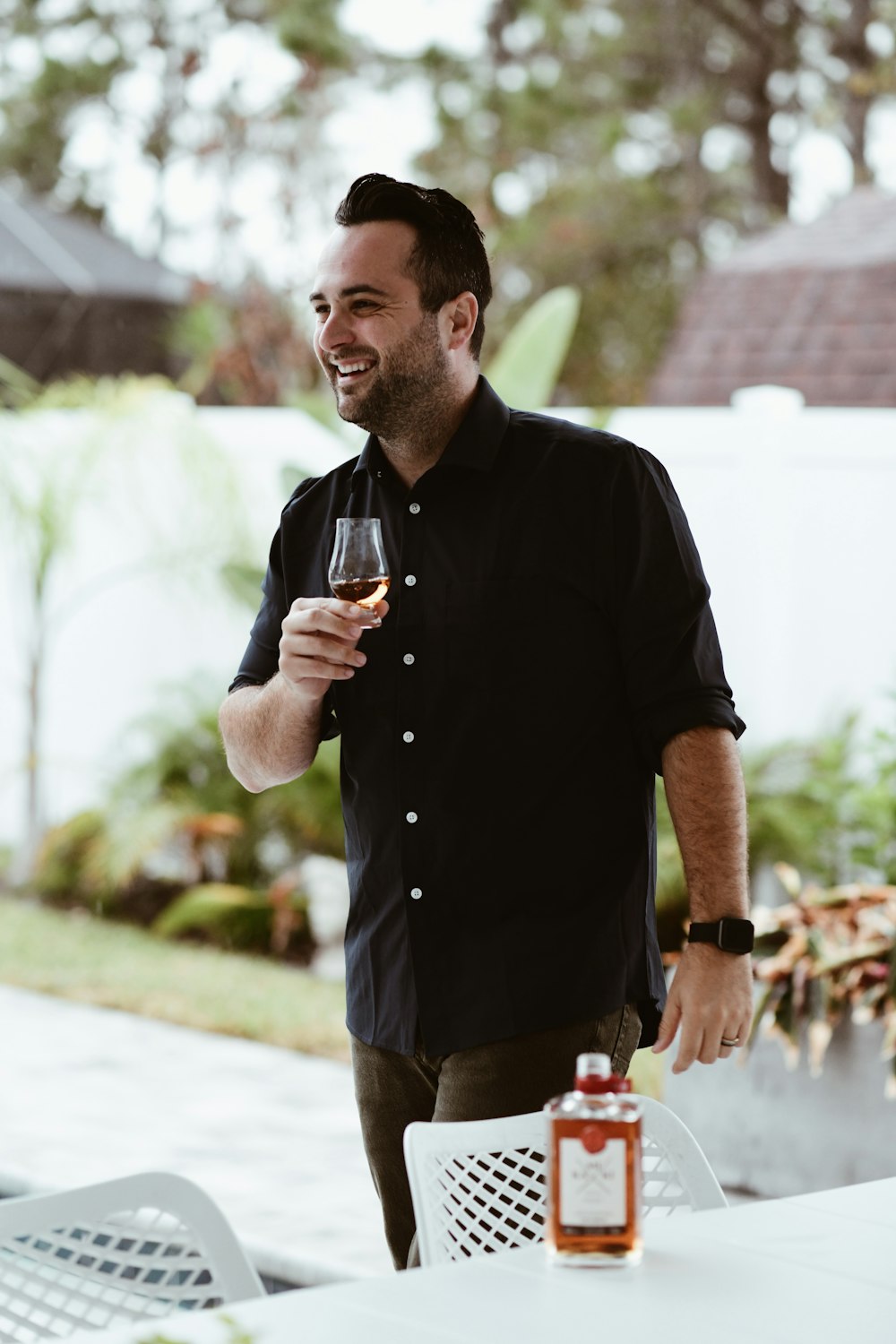 a man holding a glass of wine standing next to a table