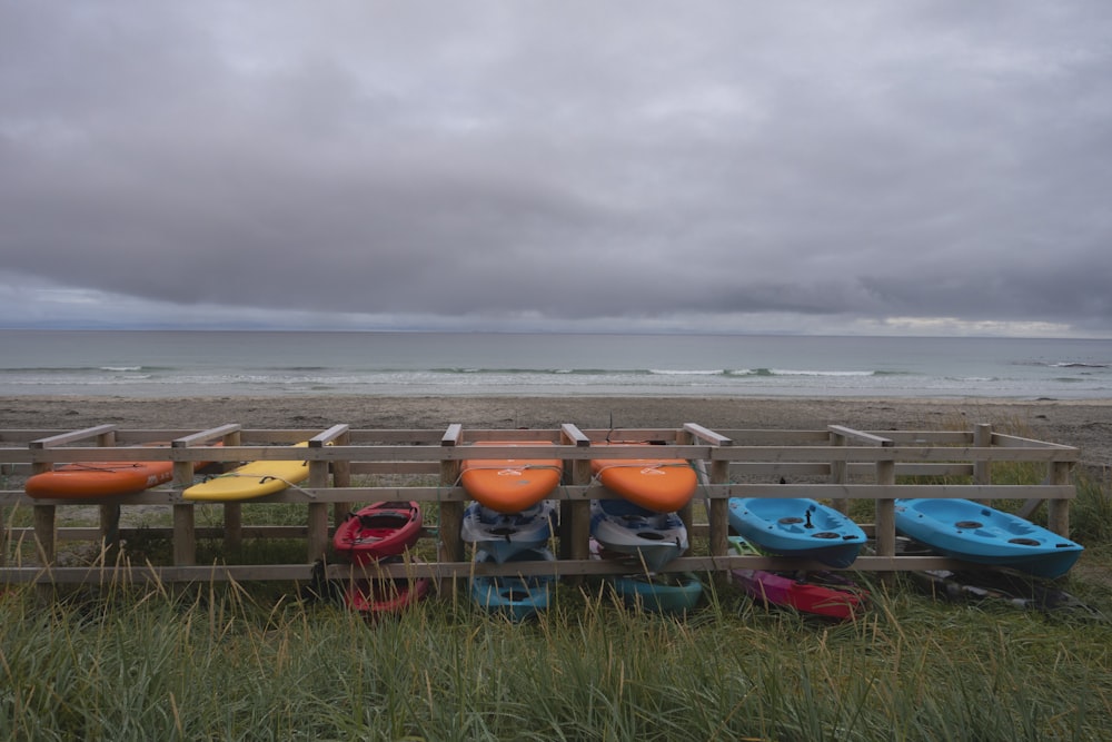 a row of kayaks sitting on top of a wooden fence