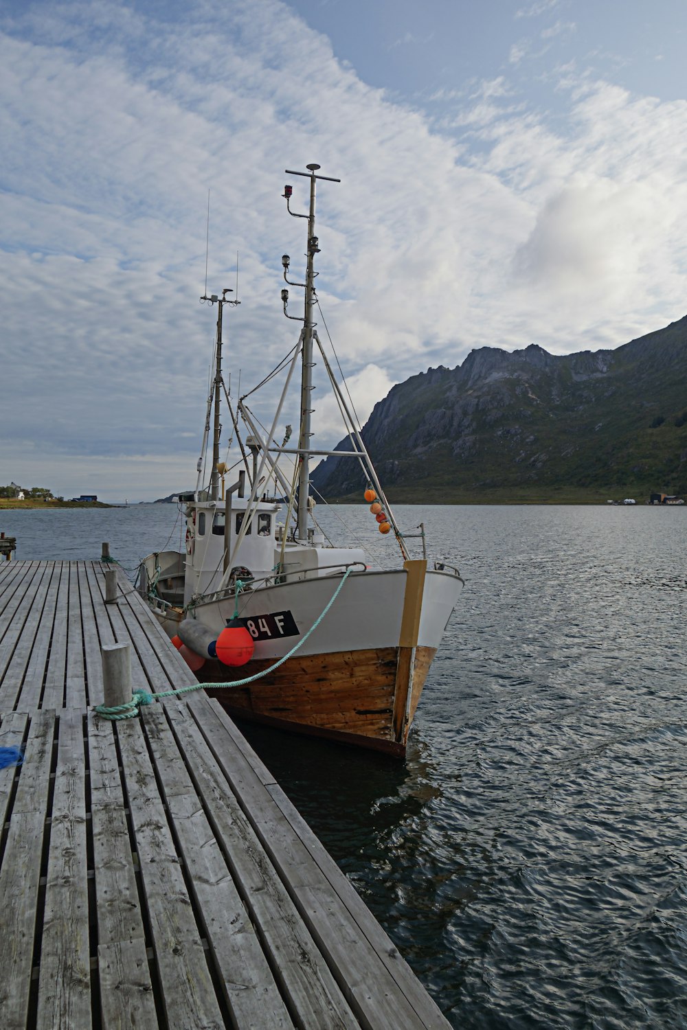 a boat docked at a pier with mountains in the background