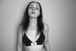 Model wearing a streamlined white blouse against a stark black background