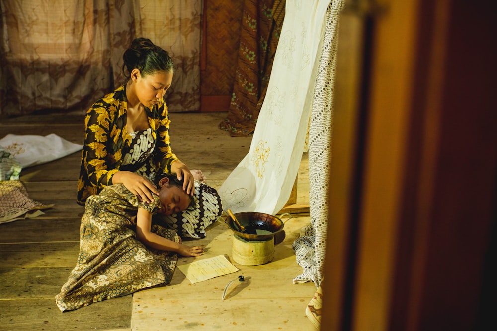 a woman sitting on the floor with a child