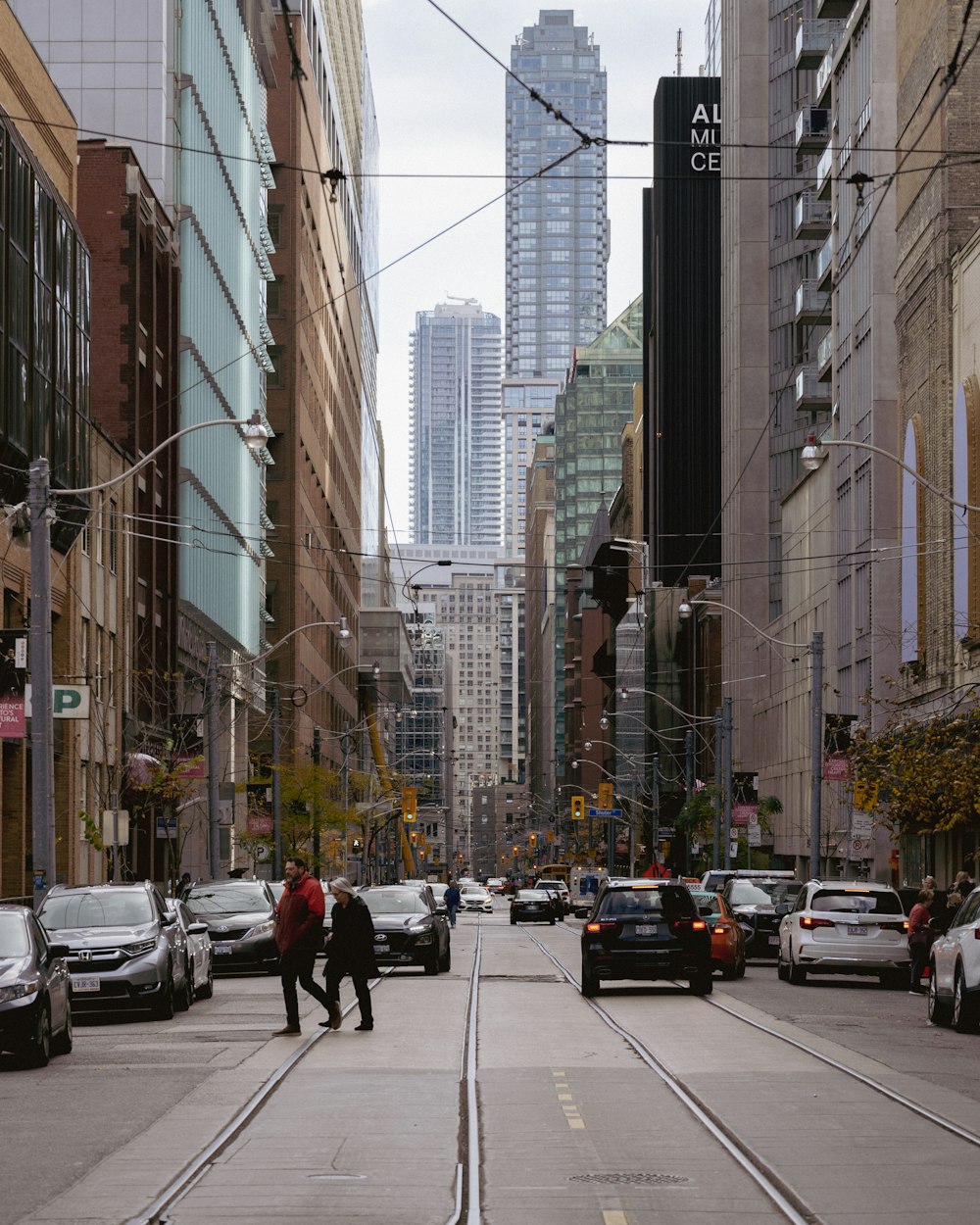 a couple of people walking down a street next to tall buildings