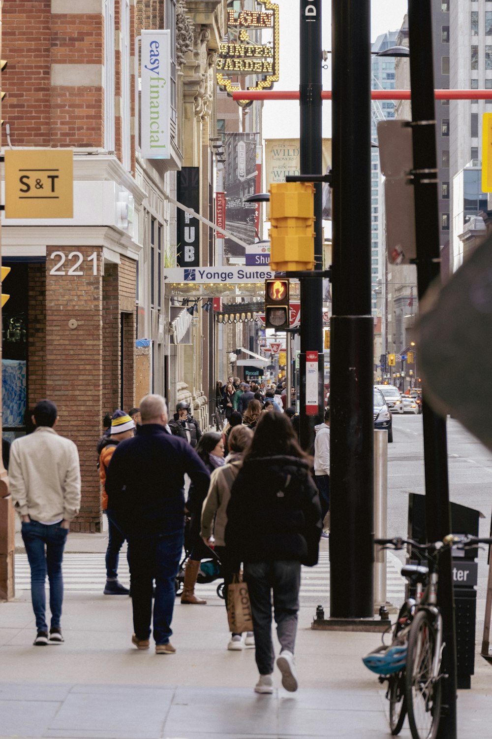 a group of people walking down a street next to tall buildings