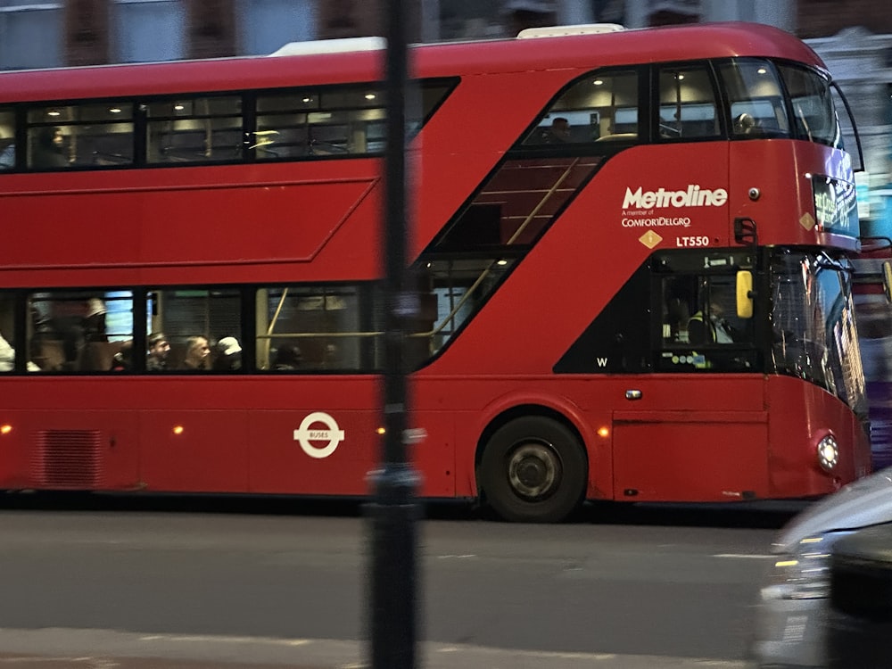 um ônibus vermelho de dois andares dirigindo por uma rua