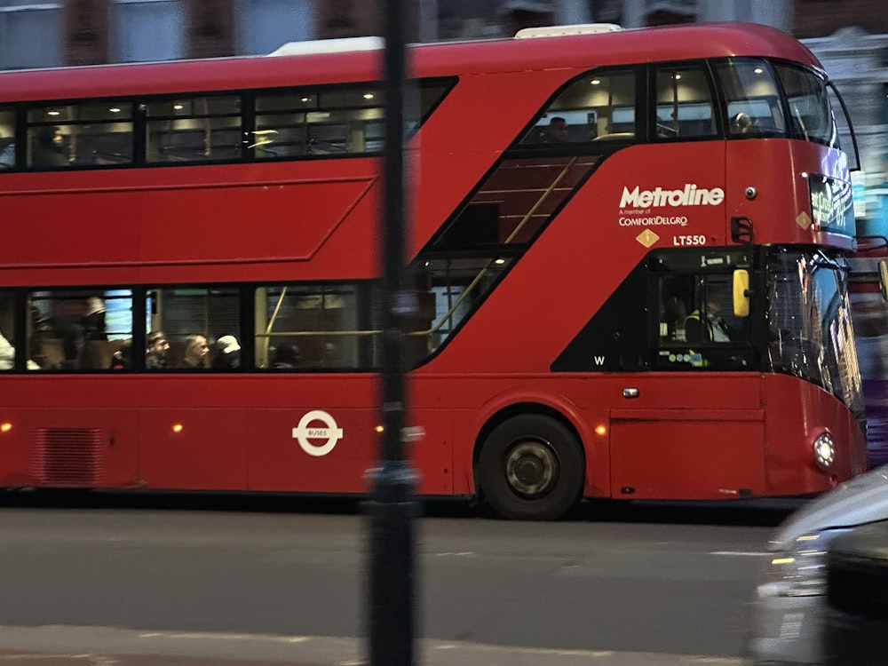 a red double decker bus driving down a street