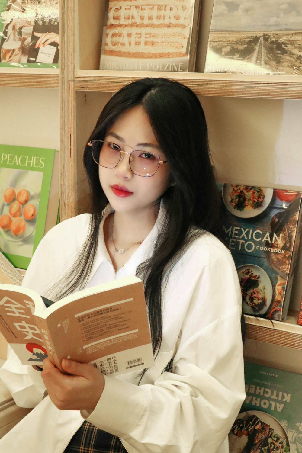 a woman wearing glasses reading a book in a bookstore