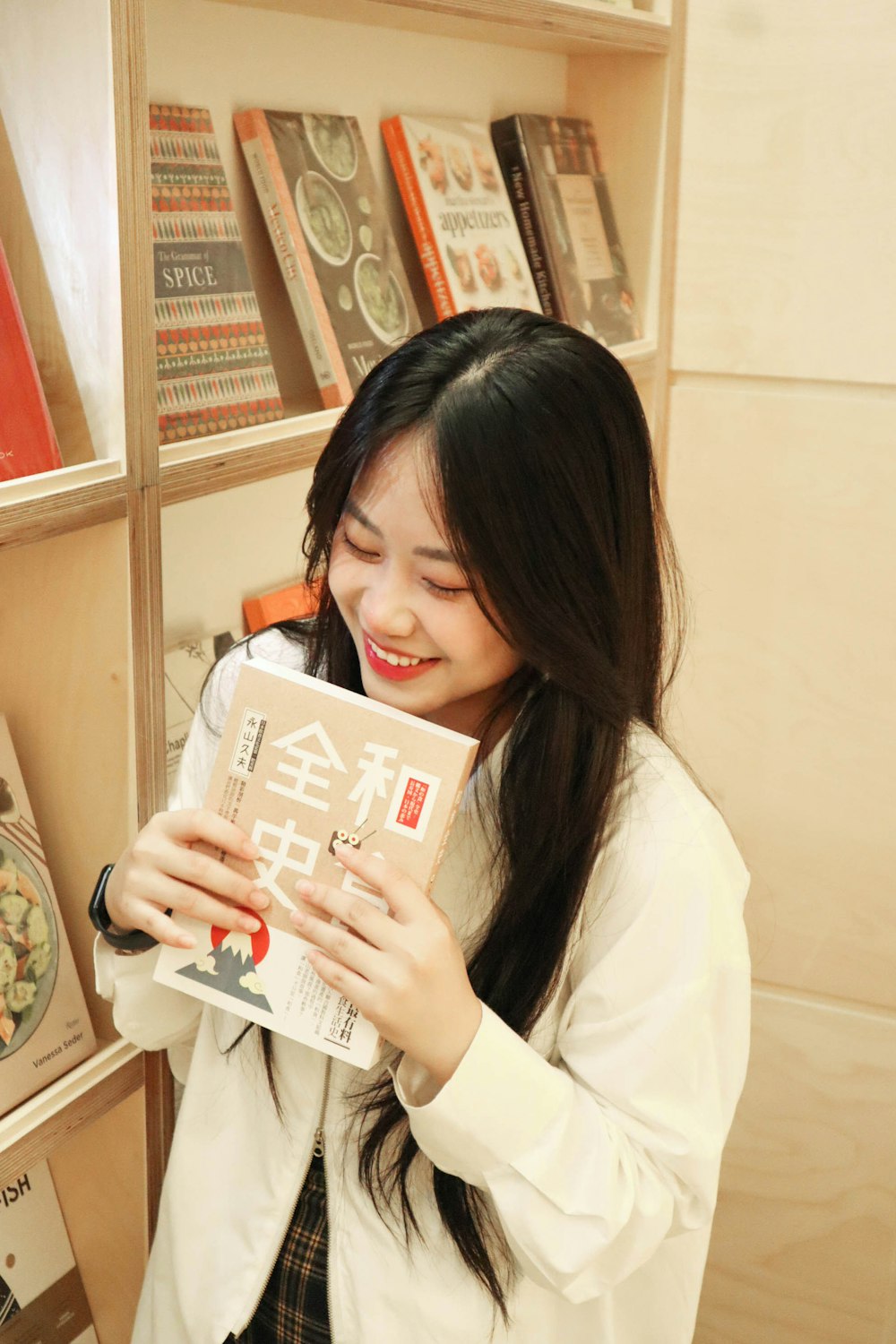a woman holding a book in front of a bookshelf