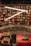 A bookstore filled with a variety of books on wooden shelves arranged in a circular pattern. Bright, white overhead lights create a modern ambiance. Decorative elements such as wrapped gifts are placed on a red, ornately designed ledge.
